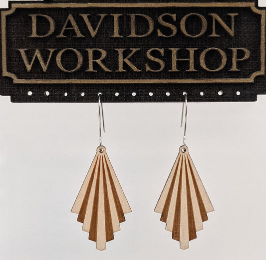 Pair of wooden earrings with silver stainless steel hooks hanging on a display. They are light and dark striped tiers in a triangular shape. Made from birch wood hanging from a model Davidson Workshop sign against a white background. (Close up View)