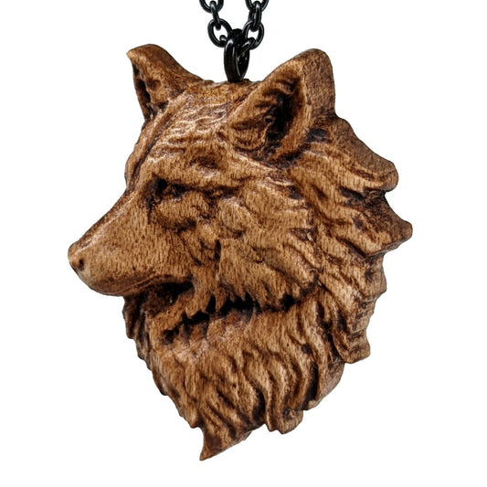 Wooden pendant necklace carved in the shape of a wolf head. The wolf faced to the side and made from hard maple wood. It hangs from a black stainless steel chain against a white background.