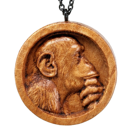 Wooden necklace pendant carved in the shape of a monkey with his hand on his chin. Made from hard maple wood and hanging from a black stainless steel chain against a white background.