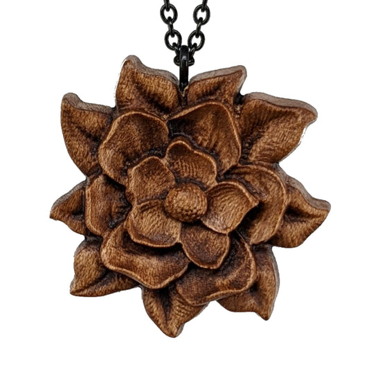 Wooden magnolia flower pendant carved in a realistic style from hard maple wood. Hanging from a black stainless steel chain against a white background.