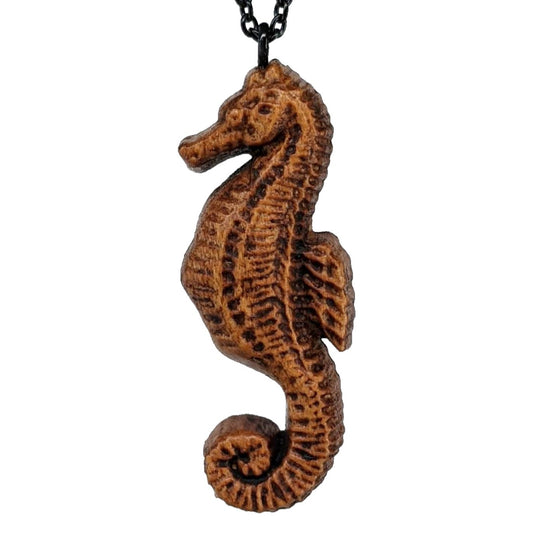 Wooden pendant necklace carved in the shape of sea horse. Made from hard maple and hanging from a black stainless steel chain against a white background.