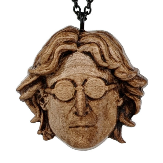Wooden pendant of a young John Lennon from the Beatles wearing glasses. Carved in a realistic style from hard maple wood. Hanging from from a black stainless steel chain.