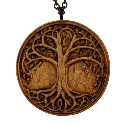 Round wooden necklace pendant. Carved from hard maple wood in the shape of a tree of of life. Hanging from a black stainless steel chain against a white background.