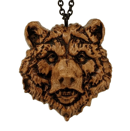 Wooden necklace pendant carved in the shape of a grizzly bears head. Made from hard maple wood. Hanging from a black stainless steel chain against a white background.