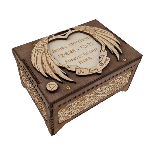 Angel wings memorial music box, dark brown and birch wood in color, tilted to show the decorative filigree patterns engraved on the front and side.