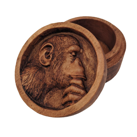 Round wooden box 3D carved with a recessed carving of a side profile view of an hairy ape rubbing his chin in his hand while in mid thought. Made from hard maple wood with a brown stain against a white background.