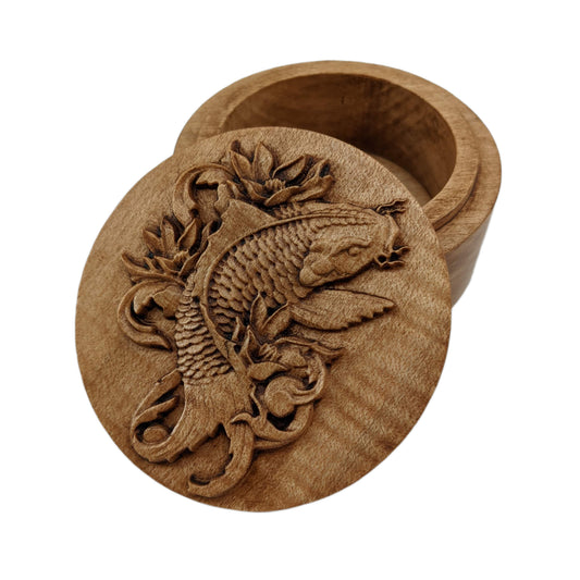 Round wooden box 3D carved with a koi fish surrounded by leaves and filigree designs. It has flowing whiskers, a sharp back fin and intricately carved scales down to its wide tail. Made from hard maple wood stained brown against a white background.