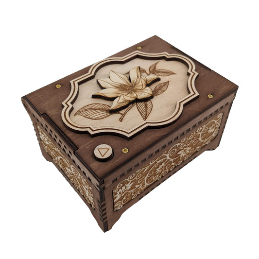 Magnolia flower music box, dark brown and birch wood in color, with decorative floral vine patterns engraved on the sides.