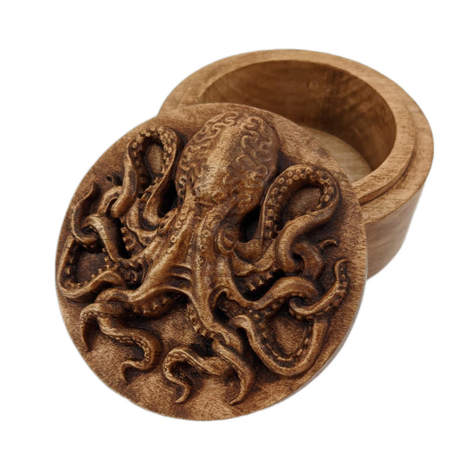 Round wooden box 3D carved with an octopus looking forward with its tentacles twisting all around. It has a bulbous head with curved markings and suction cups all down its arms. Made from hard maple wood stained brown against a white background.
