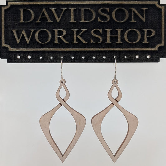 Pair of wooden earrings with silver stainless steel hooks. They are light natural finish elongated infinity symbols with sharp points. Made from birch wood hanging from a model Davidson Workshop sign against a white background. (Close up View)