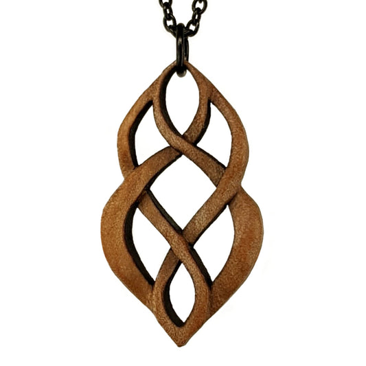 Wooden necklace pendant carved so that curving shapes weave into each other. Made from hard maple wood and hanging from a black chain against a white background.