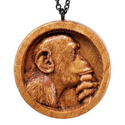 Wooden necklace pendant carved in the shape of a monkey with his hand on his chin. Made from hard maple wood and hanging from a black stainless steel chain against a white background.