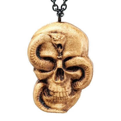 Wooden necklace pendant carved in the shape of a skull with a snake crawling through the eyes. Made from hard maple wood and hanging from a black stainless steel chain against a white background.