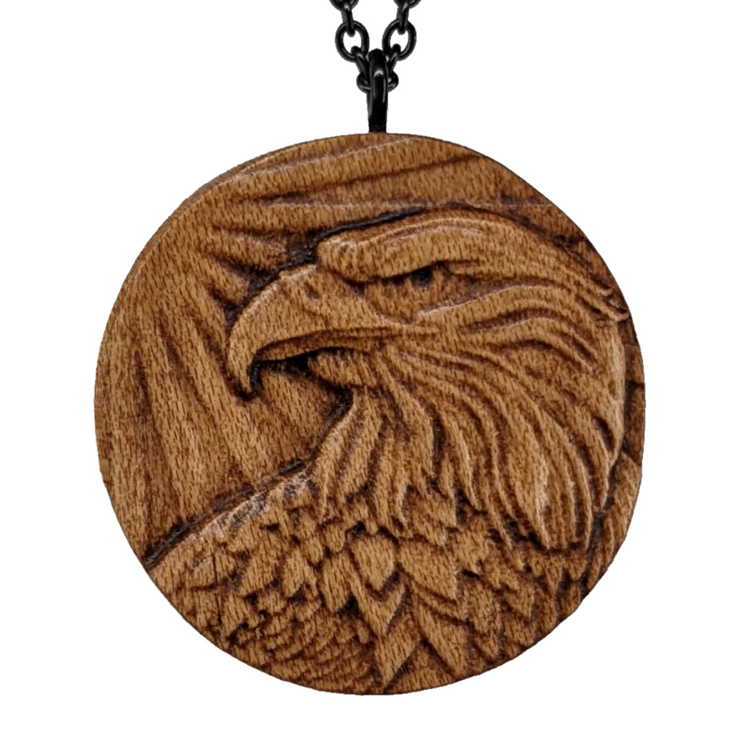 Round wooden necklace pendant carved in the shape of an eagles head. Made from hard maple wood. Hanging from a black stainless steel chain against a white background.