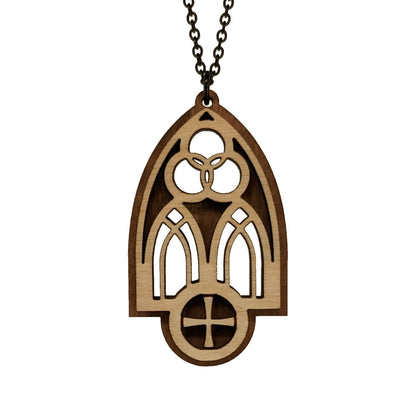 Wooden necklace pendant inspired by a gothic church window. includes a trinity symbol above and a cross below. Made from two layers, dark and light birch wood. Hanging from a black stainless steel chain against a white background.