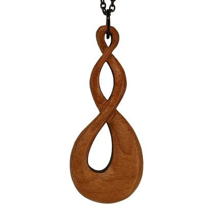 Wooden necklace pendant carved in the shape of a twisted infinity inspired symbol. Made from cherry wood. Hanging from a black stainless steel chain against a white background.