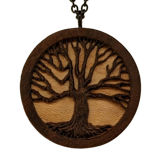 Round necklace pendant carved from contrasting hardwoods. A dark walnut tree overlayed against a light maple base. Hanging from a black stainless steel chain against a white background.