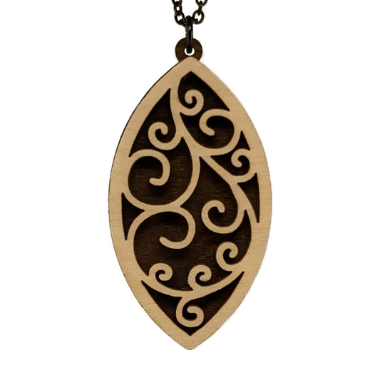 Wooden filagree pendant necklace made of contrasting layers of light and dark birch wood. The swirl pattern is light in color overlayed onto a darker base. Hanging from a black stainless steel chain against a white background.