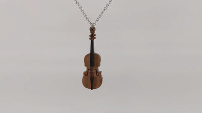 Wooden necklace pendant created in the shape of a miniature cello stand of bass. Made from cherry wood. Hanging and rotating from a silver stainless steel chain against a white background.