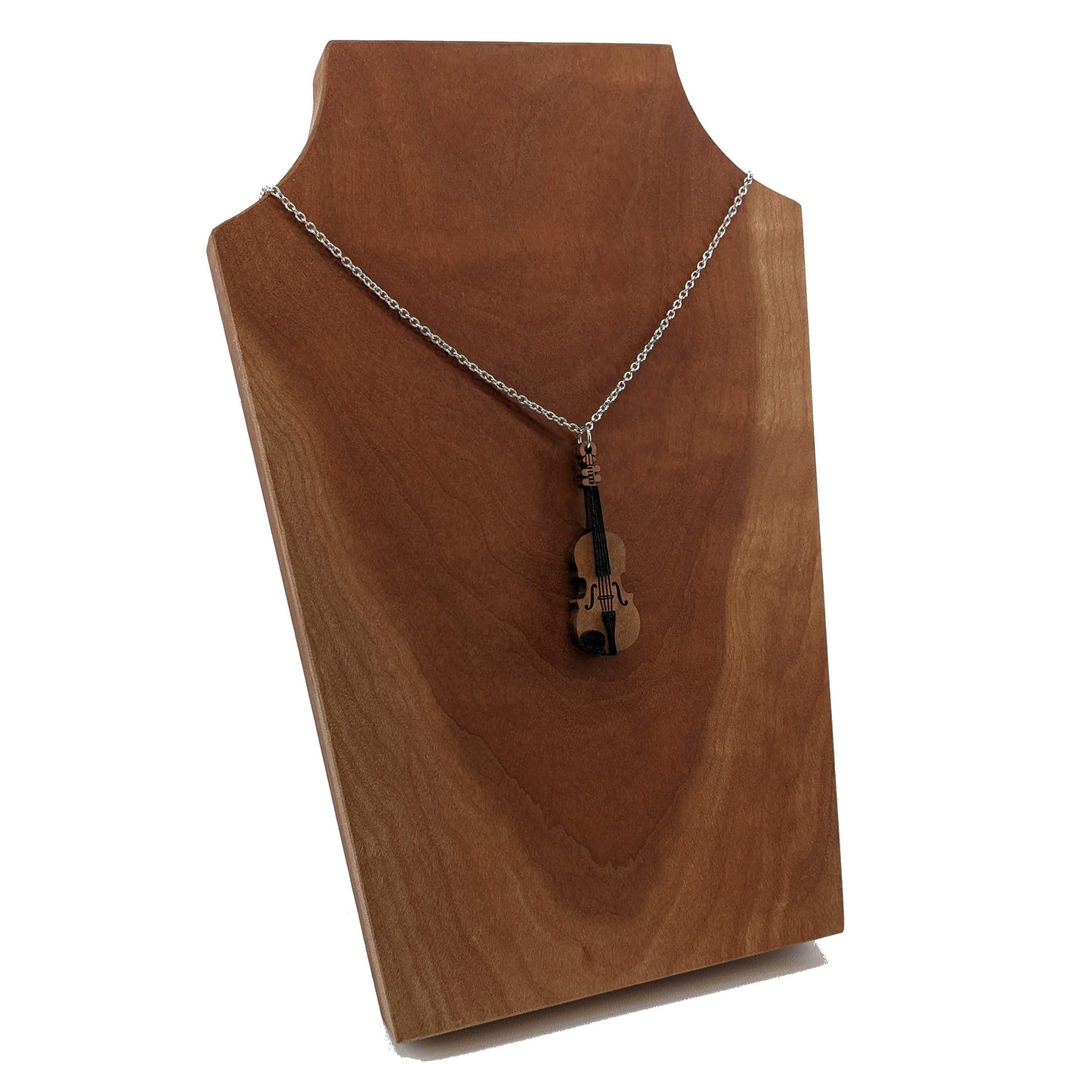 Wooden necklace pendant created in the shape of a miniature violin. Made from hard maple wood and hanging from a silver stainless steel chain against a cherry wood background.