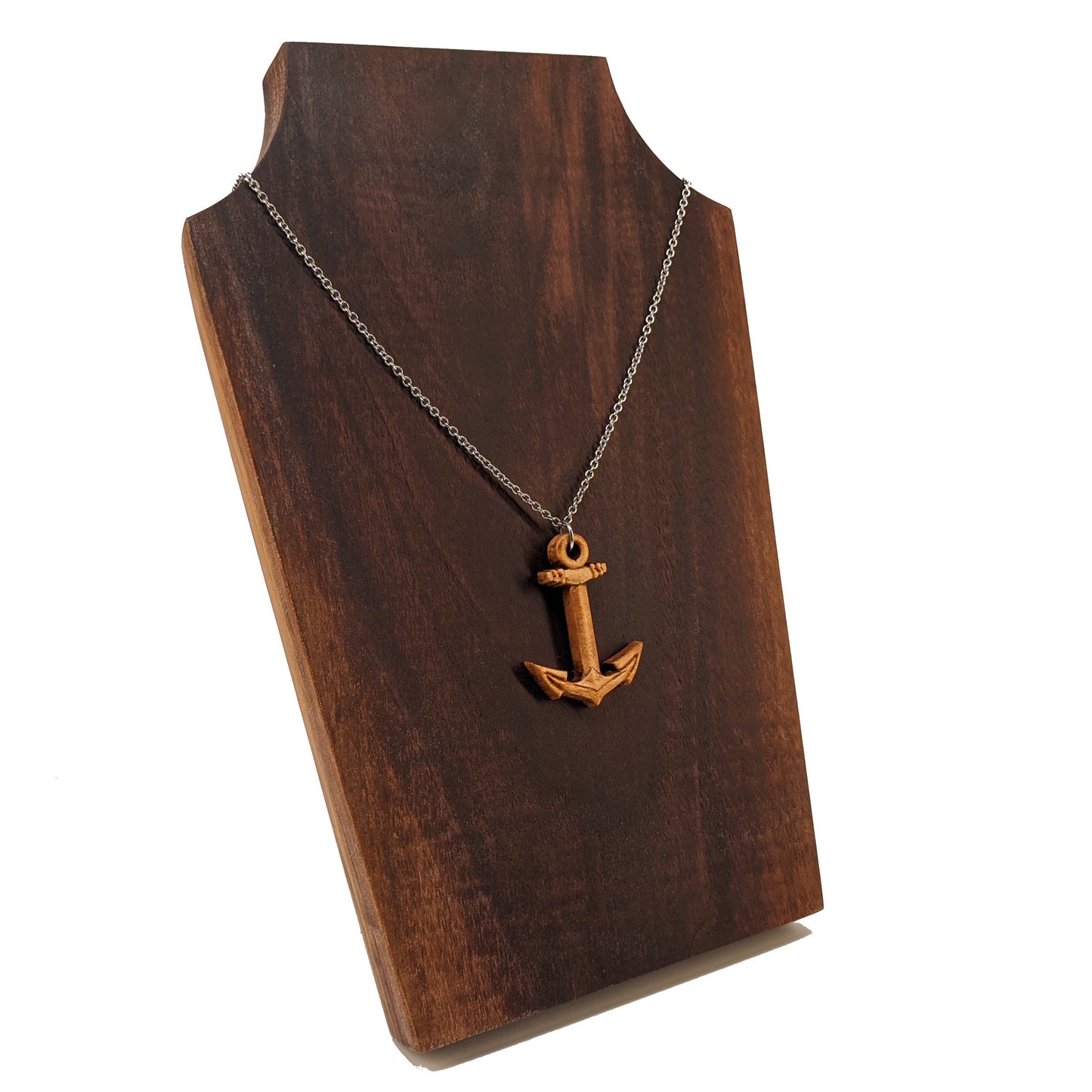 Wooden pendant necklace carved in the shape of a anchor. Made from hard maple wood. It hangs from a silver stainless steel chain against a dark walnut display.