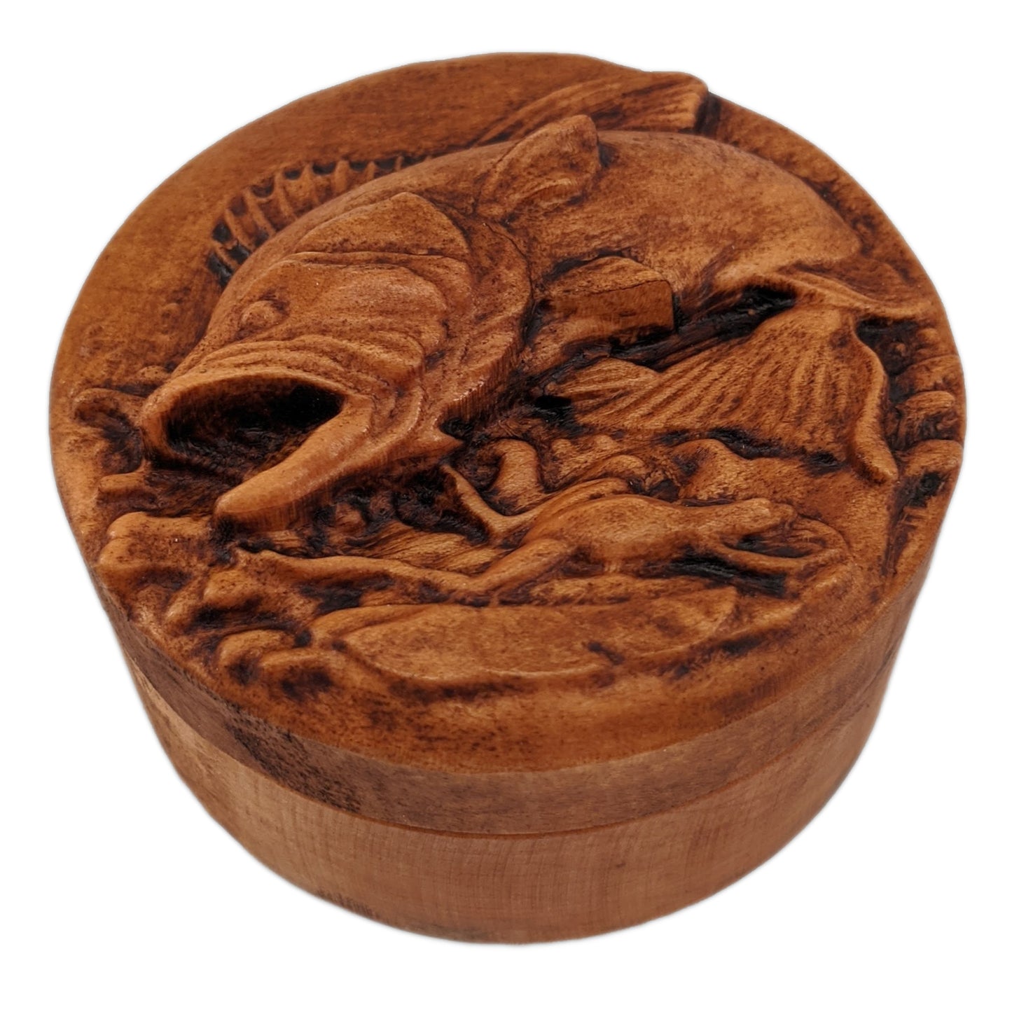 Round wooden box 3D carved with a large bass fish jumping out of the water chasing after a small frog that has narrowly avoided being caught. Both are overtop a watery splash. Made from hard maple wood with a brown stain against a white background.Round wooden box 3D carved with a large bass fish jumping out of the water chasing after a small frog that has narrowly avoided being caught. Both are overtop a watery splash. Made from hard maple wood with a brown stain against a white background.