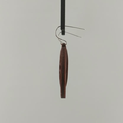 Pair of wooden earrings with silver stainless steel hooks. They are brown round with symmetrical petal shaped cutouts within. Made from birch wood hanging and rotating against a white background.