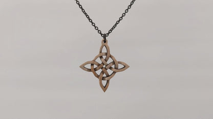 Wooden necklace pendant created in the style of a Celtic woven cross. Made from maple wood.Wooden necklace pendant created in the style of a Celtic woven cross. Made from maple wood. Hanging and rotating from a black stainless steel chain against a white background.