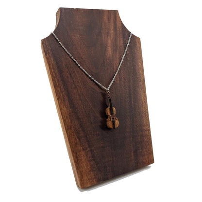 Wooden necklace pendant created in the shape of a miniature cello stand up bass. Made from cherry wood and hanging from a silver stainless steel chain against a dark walnut background.