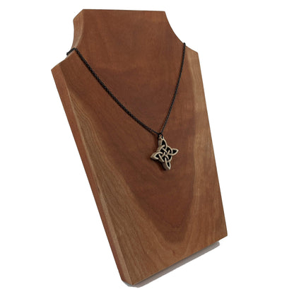 Wooden necklace pendant created in the style of a Celtic woven cross. Made from hard maple wood.  Hanging from a black stainless steel chain against a cherry wood background.