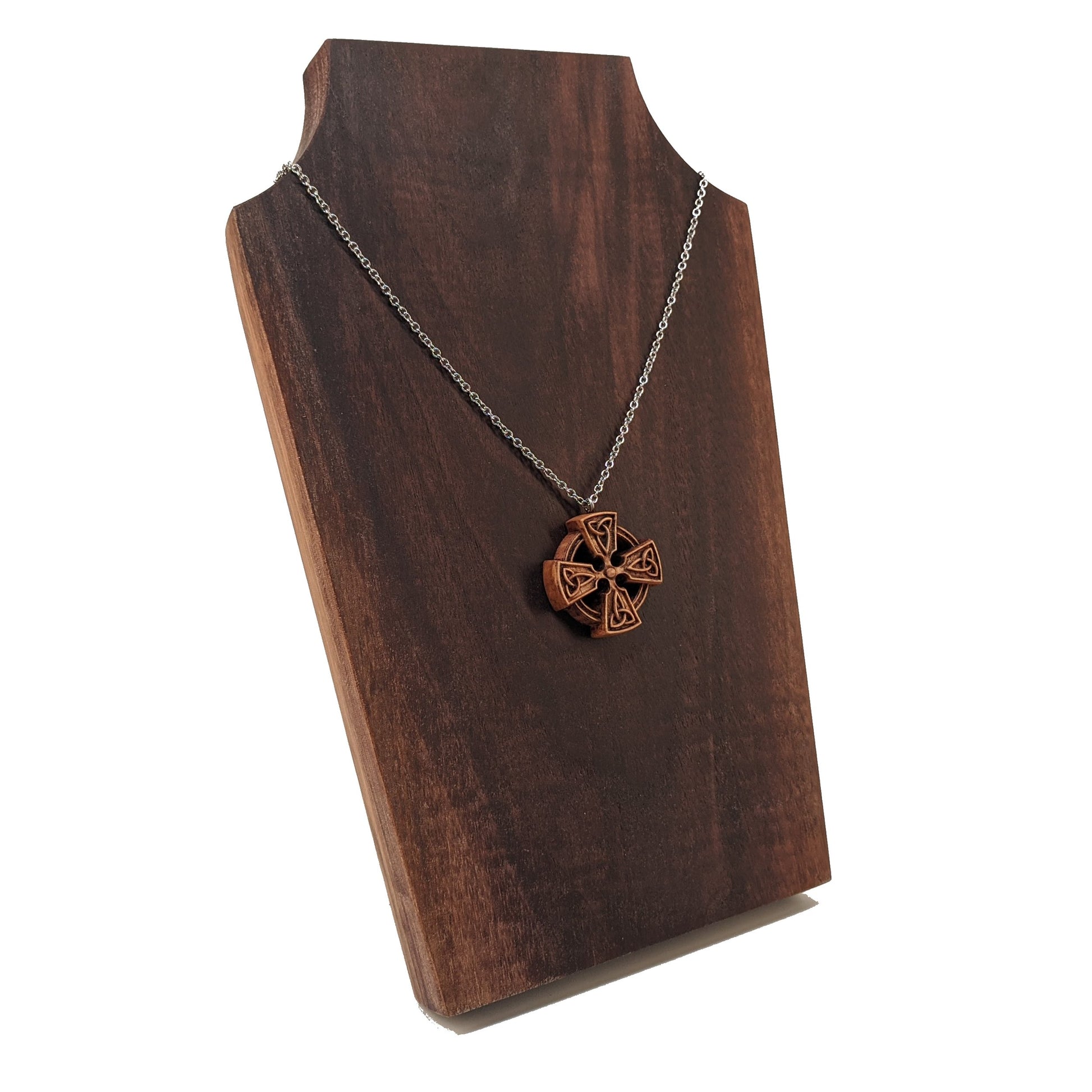 Wooden necklace pendant created in the shape of a Celtic cross. Made from hard maple wood and hanging from a silver stainless steel chain against a dark walnut display.