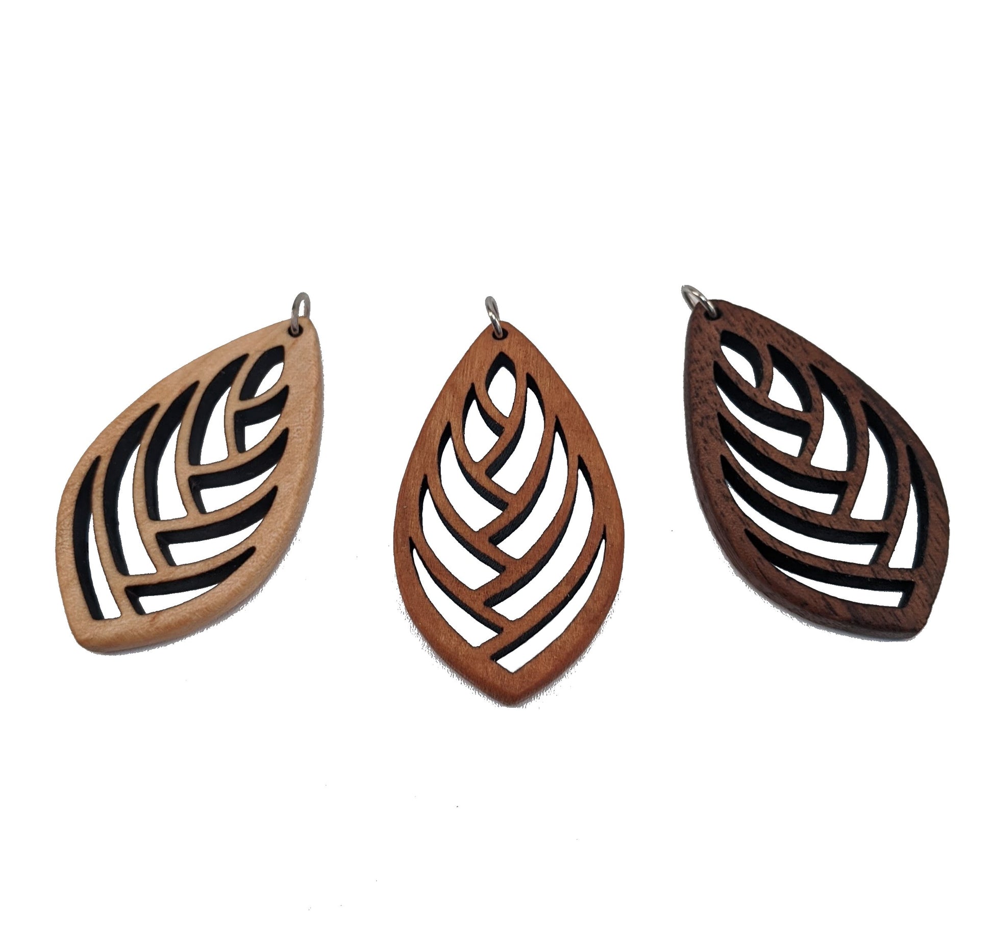 3 wooden necklace pendants cut into a teardrop shape with a herring bone pattern cut throughout them. Made from hard maple, cherry and walnut lying against a white background.