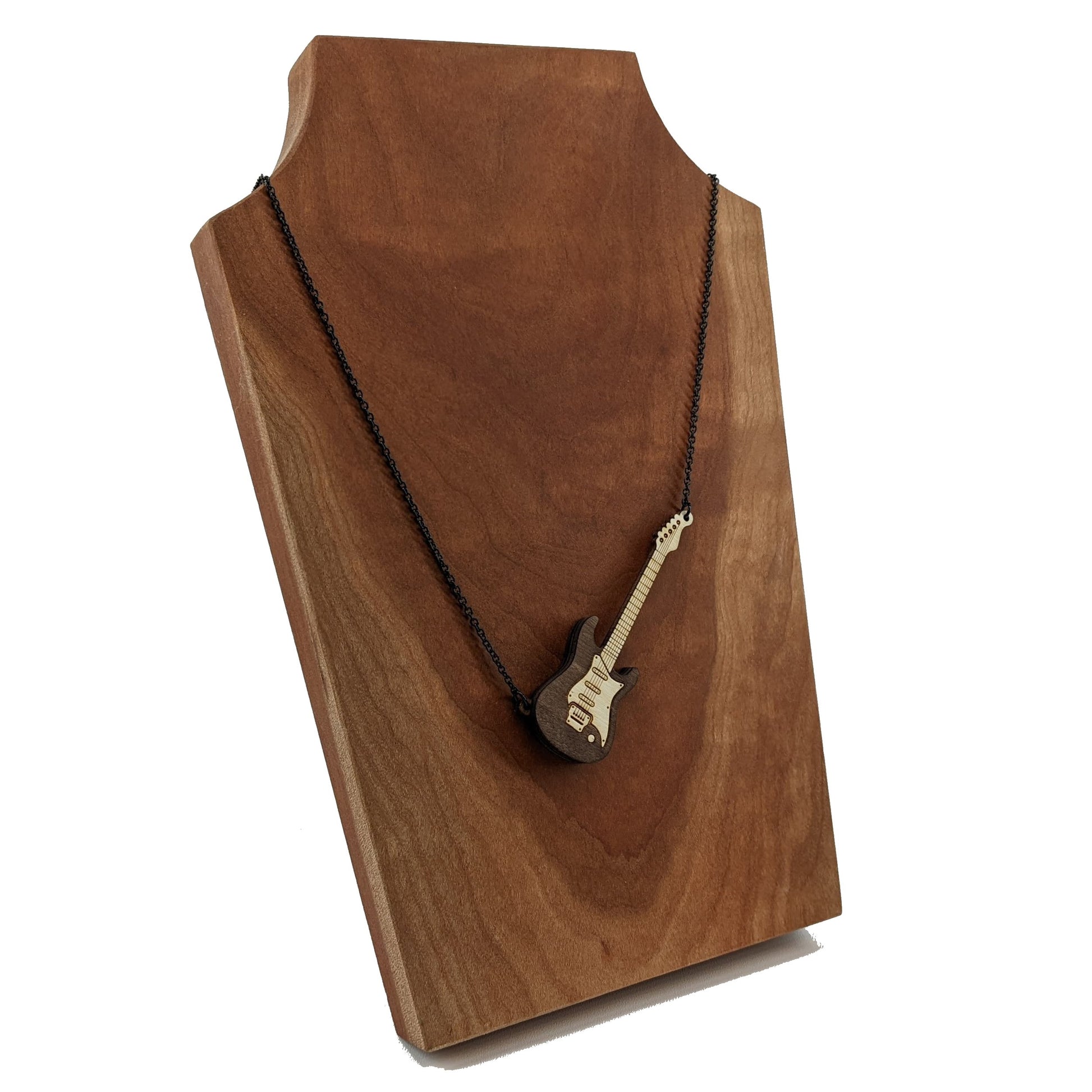 Electric guitar shaped wooden necklace pendant. Made from birch wood and stained dark brown. Hanging from a black stainless steel chain against a cherry wood background.