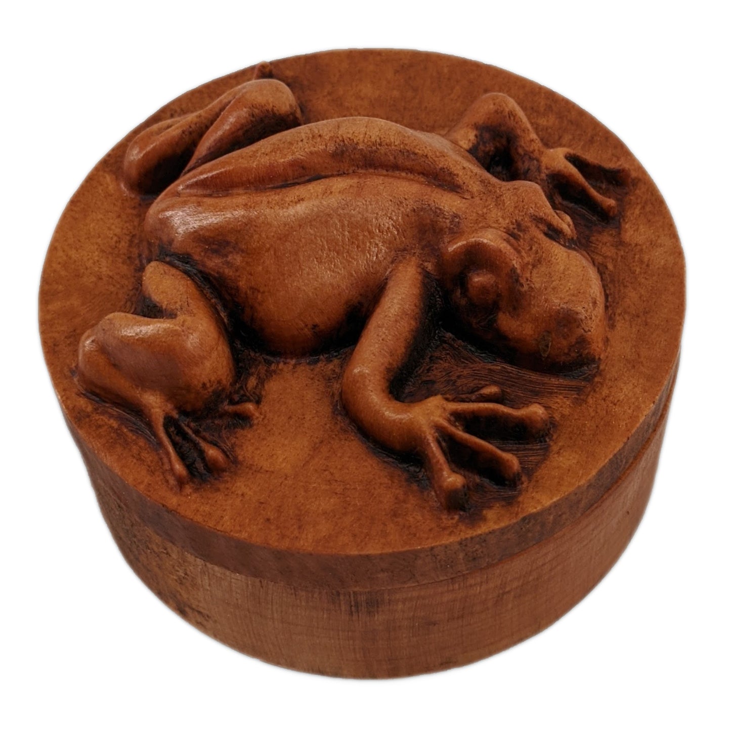 Round wooden box 3D carved with a tree frog in a clinging position. It has smooth skin and long skinny limbs and hands with bulbous fingertips Made from hard maple wood with a brown stain against a white background.