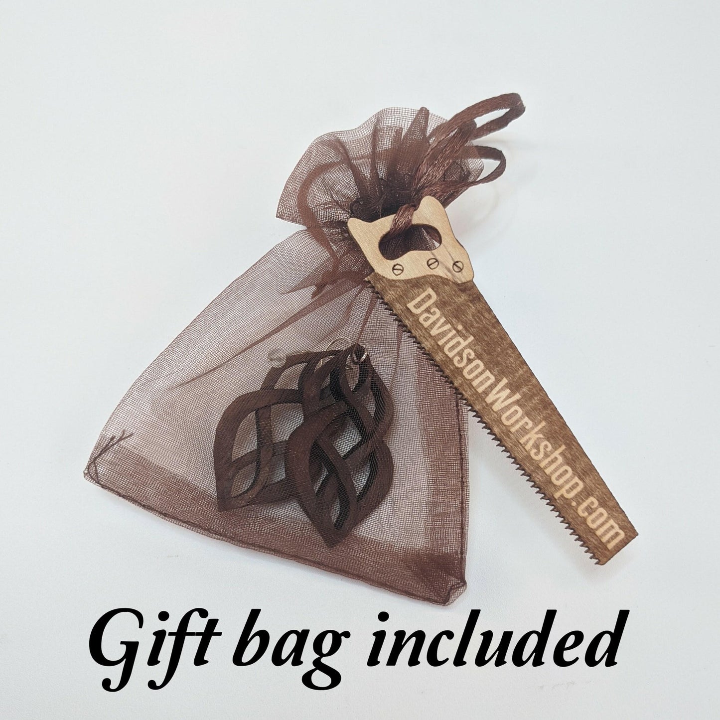 Brown shear gift bag filled with example pair of earrings with a wooden business card shaped like a saw that reads DavidsonWorkshop.com, all against a white background.