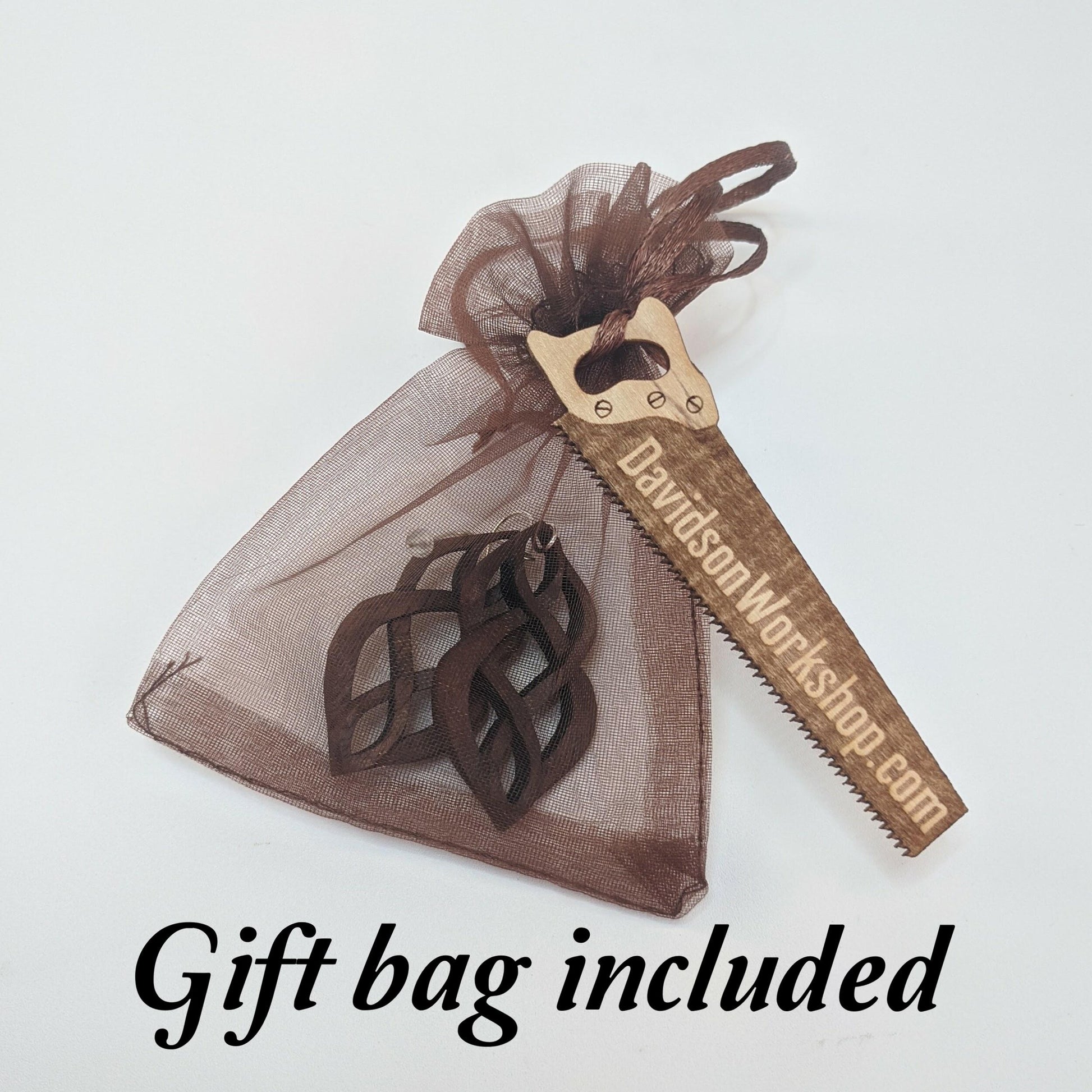 Brown shear gift bag filled with example pair of earrings with a wooden business card shaped like a saw that reads DavidsonWorkshop.com, all against a white background.