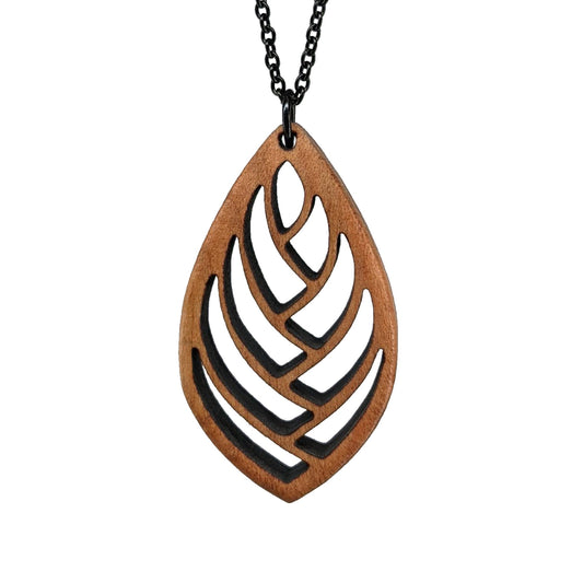 Wooden necklace pendant cut into a teardrop shape with a herring bone pattern cut throughout it. Made from hard maple and hanging from a black stainless steel chain against a white background.