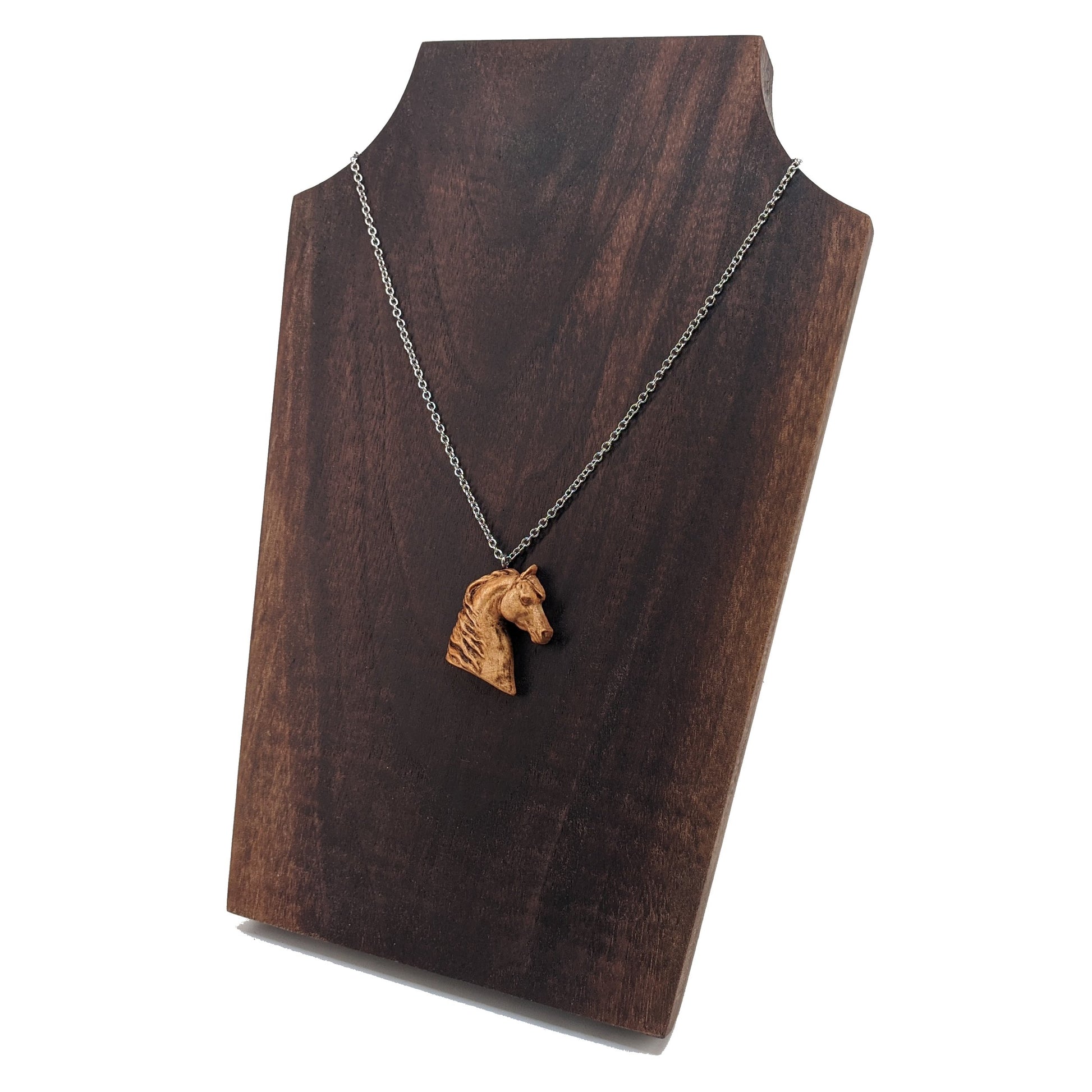 Wooden pendant realistically carved in the shape of a horse. Made form hard maple and hung from a silver stainless steel chain against a dark walnut display.