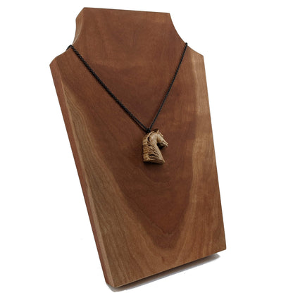 Wooden pendant realistically carved in the shape of a horse. Made form hard maple and hung from a black stainless steel chain against a cherry wood background.