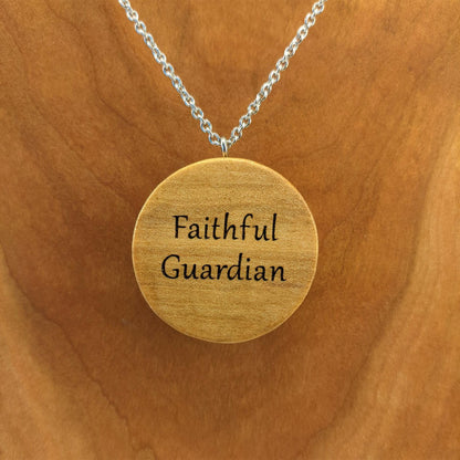 Round wooden necklace pendant hanging from a silver chain. Engraved with a personalized engraving on the back.