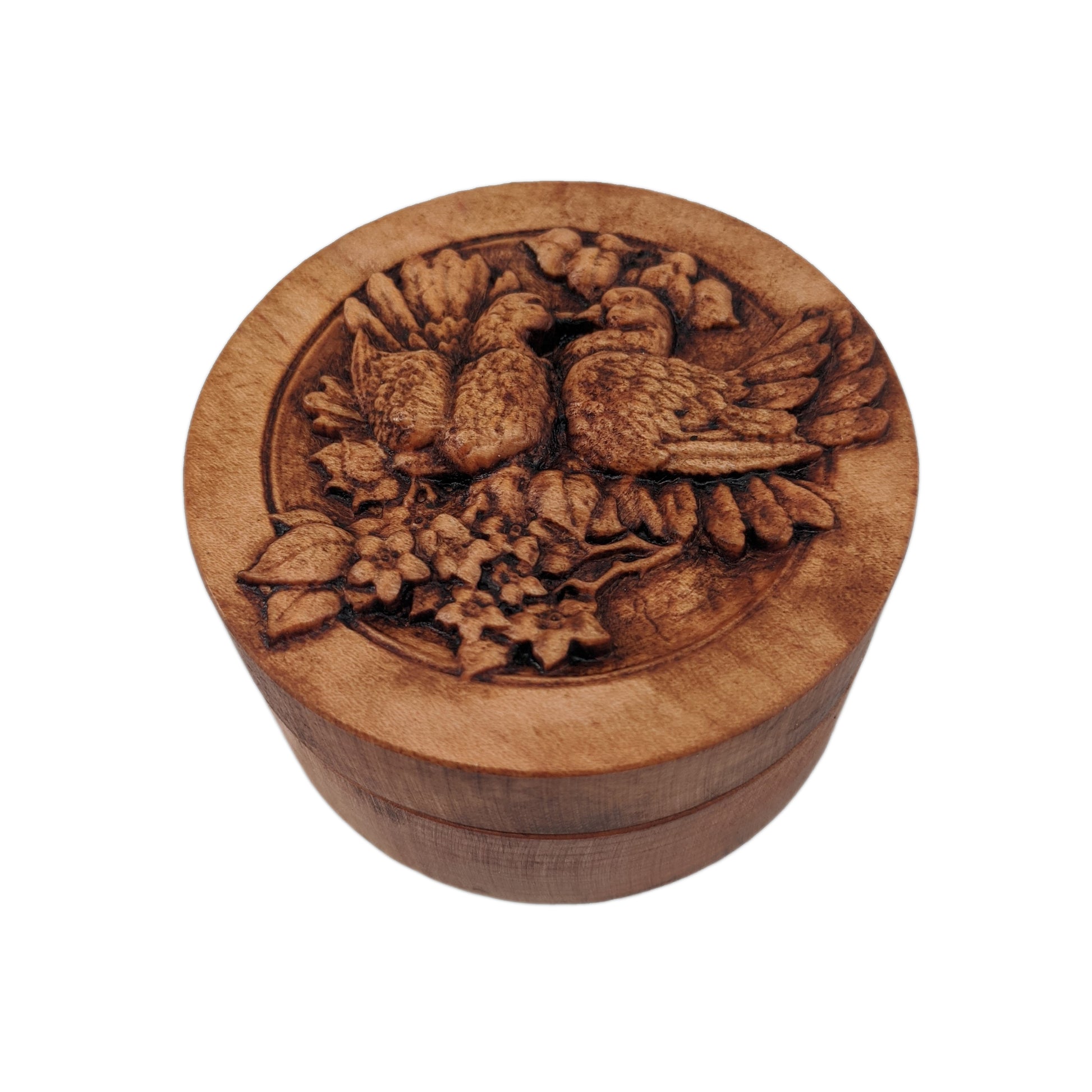 Round wooden box 3D carved with two lovebirds standing on a branch blooming with flowers, looking at each other with their beaks touching and feathers fluffed up. Made from hard maple wood stained brown against a white background.