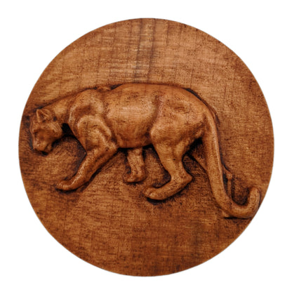 Round wooden box 3D carved with a mountain lion standing broadside to the left. It has a sleek body with its head bent toward the ground and a long tail that hangs to its feet. Made from hard maple wood stained brown against a white background.