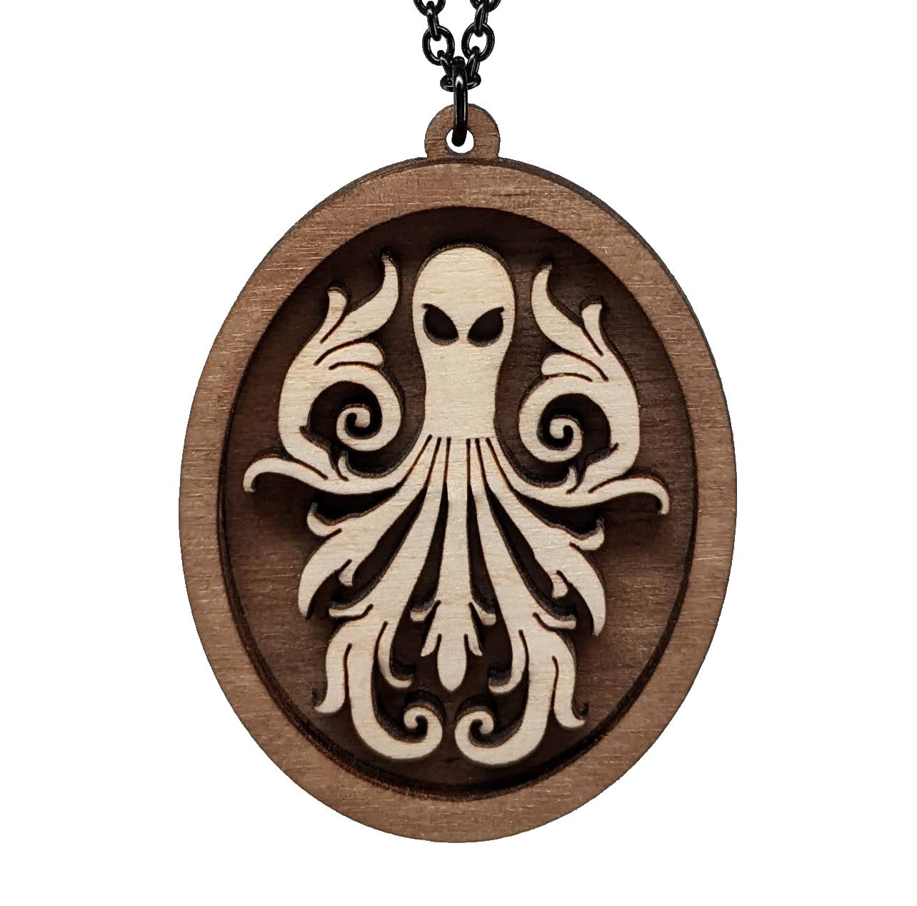 Oval wooden octopus pendant necklace made of contrasting layers of light and dark birch wood. The Octopus is light in color overlayed onto a darker base. Hanging from a black stainless steel chain against a white background.