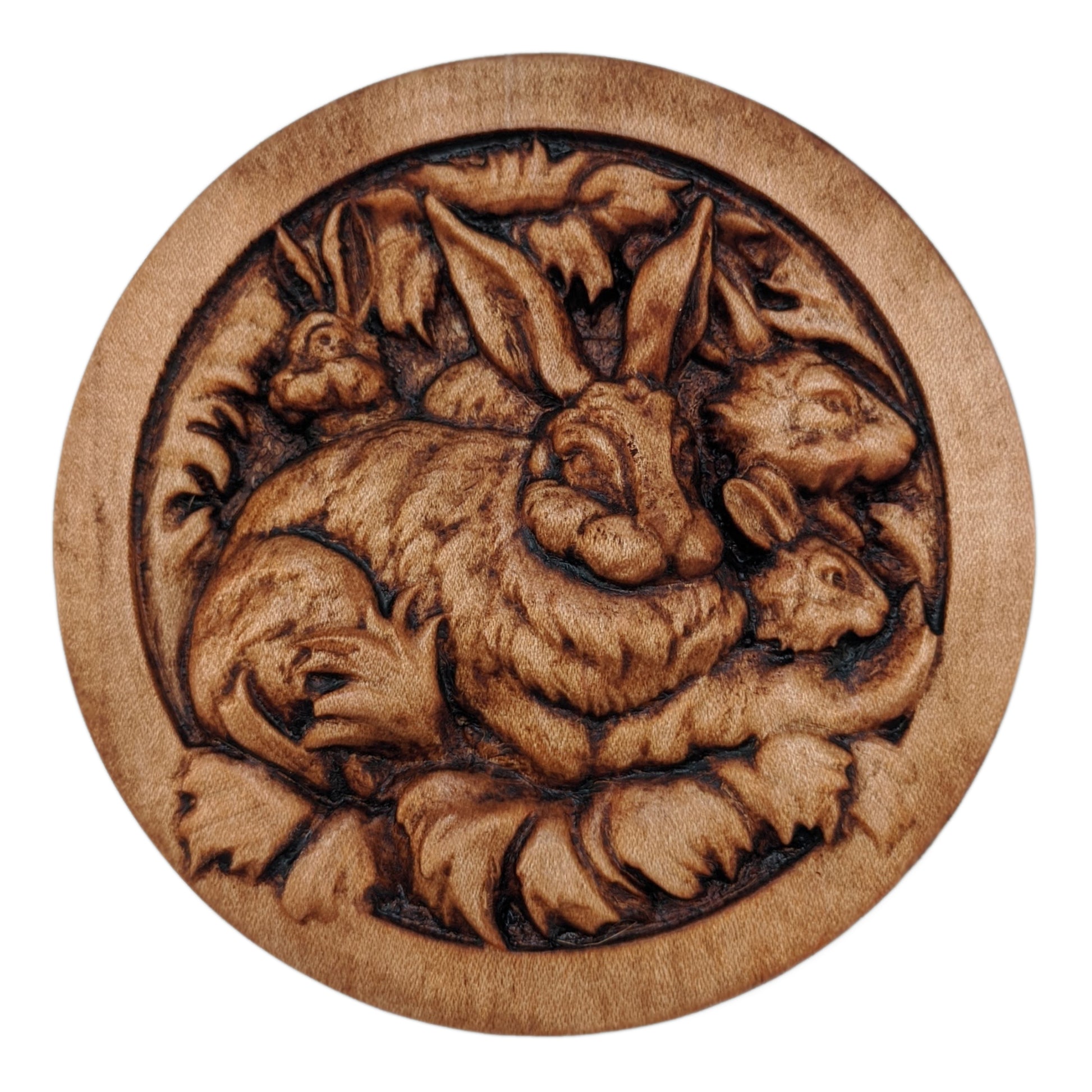 Round wooden box 3D carved with a family of rabbits together in their nest. Mother rabbit has bushy fur, tall ears and  heads of three baby rabbits peaking out from behind her. Made from hard maple wood stained brown against a white background.