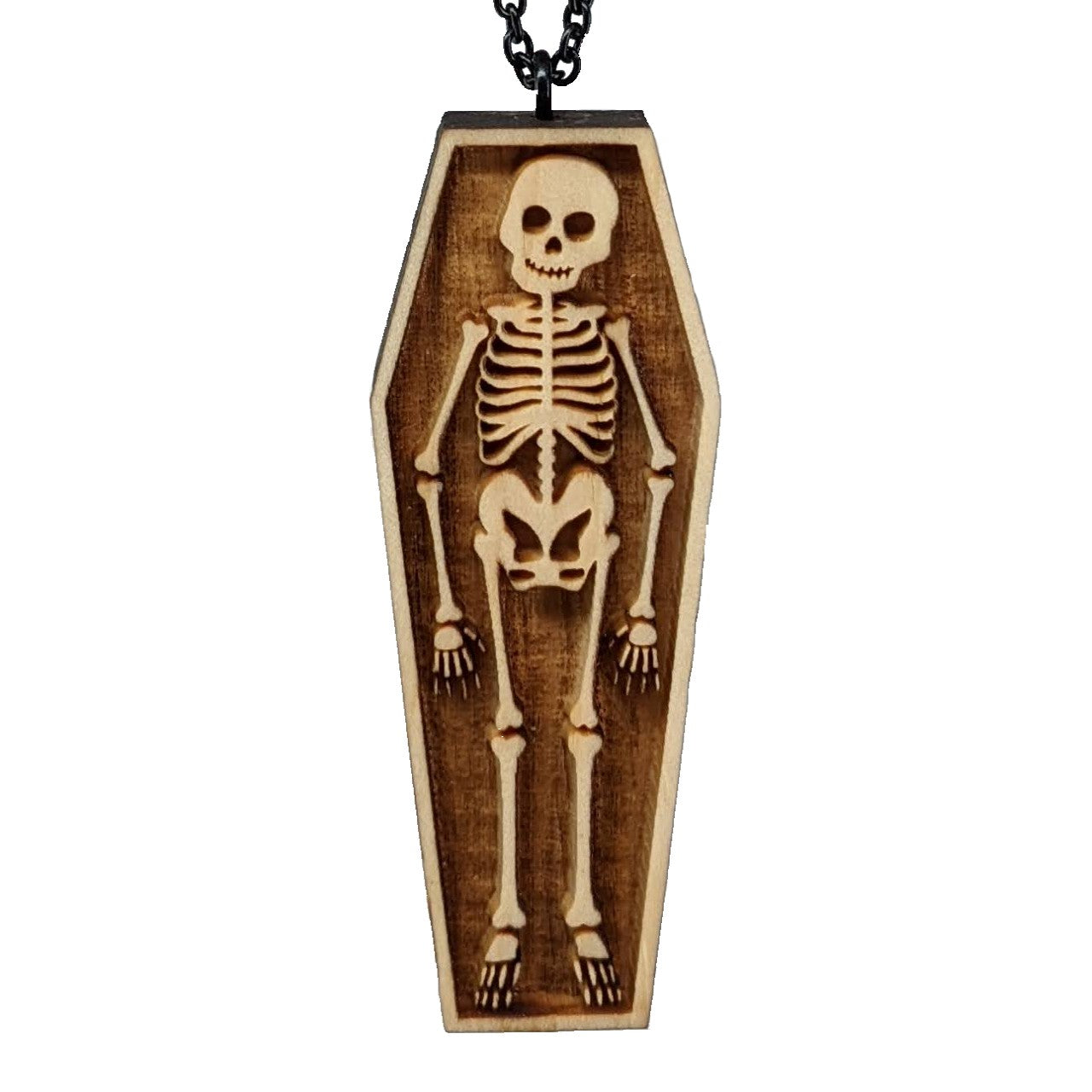 Wooden necklace pendant created in the shape a skeleton lying in a coffin. Hanging from a black stainless steel chain against a white background.